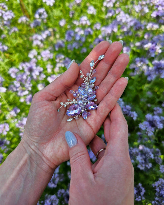 a woman's hand holding a ring with a flower on it