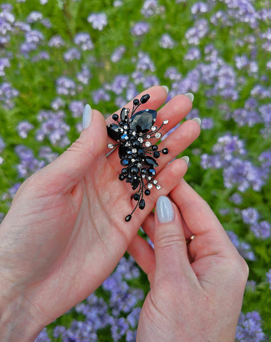 a woman's hand holding a ring in front of a field of flowers