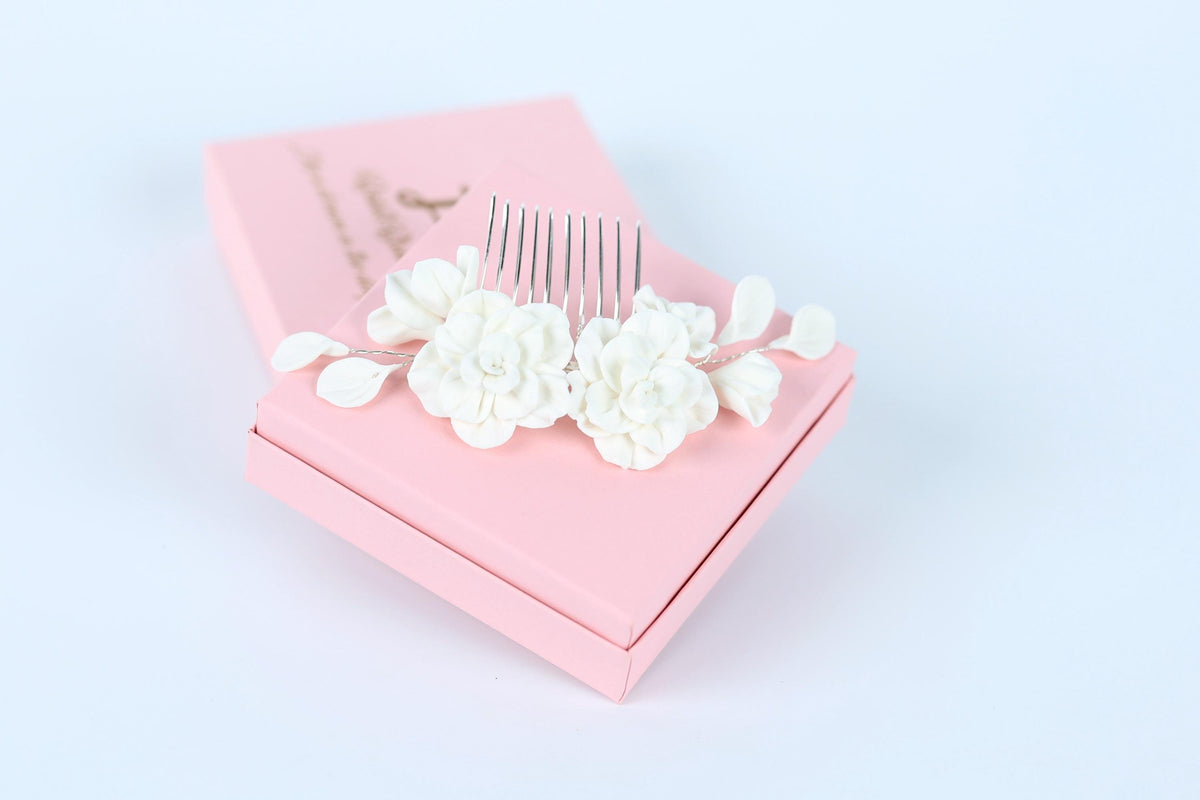 A pink box with a decorative comb and white flower-like objects on top, placed on a white background.