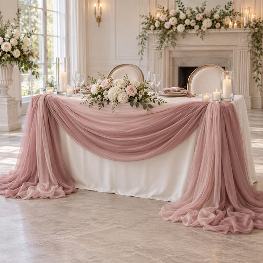 a beautifully decorated wedding reception table with a white tablecloth, pink and white floral arrangements, and a draped table runner. The table is set with wine glasses, plates, and candles, creating an elegant and romantic atmosphere.