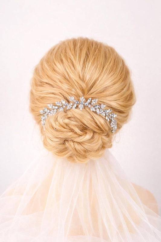 a woman's blonde hair styled in a bun, with a decorative hair accessory, possibly a veil or hairpiece, placed on top of her head.