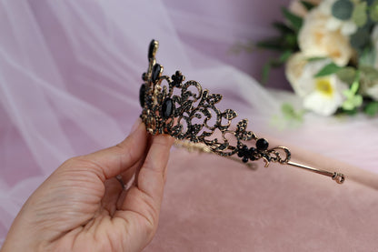 a hand holding a tiara with flowers in the background
