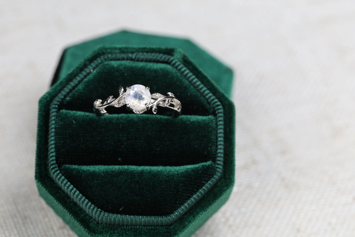 a green velvet ring box with a ring in it