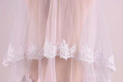 A close-up view of a delicate white wedding veil with intricate lace detailing.
