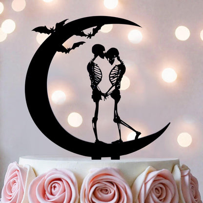 A black silhouette of a skeleton couple embracing on a crescent moon, with bats flying above them, is the central focus of the image.