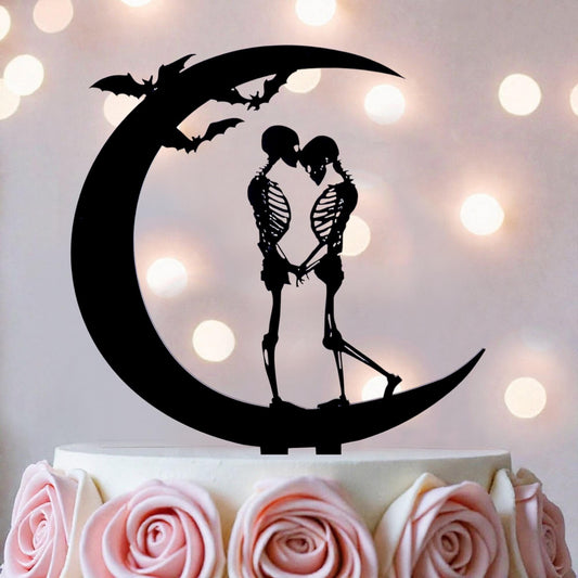 A black silhouette of a skeleton couple embracing on a crescent moon, with bats flying above them, is the central focus of the image.