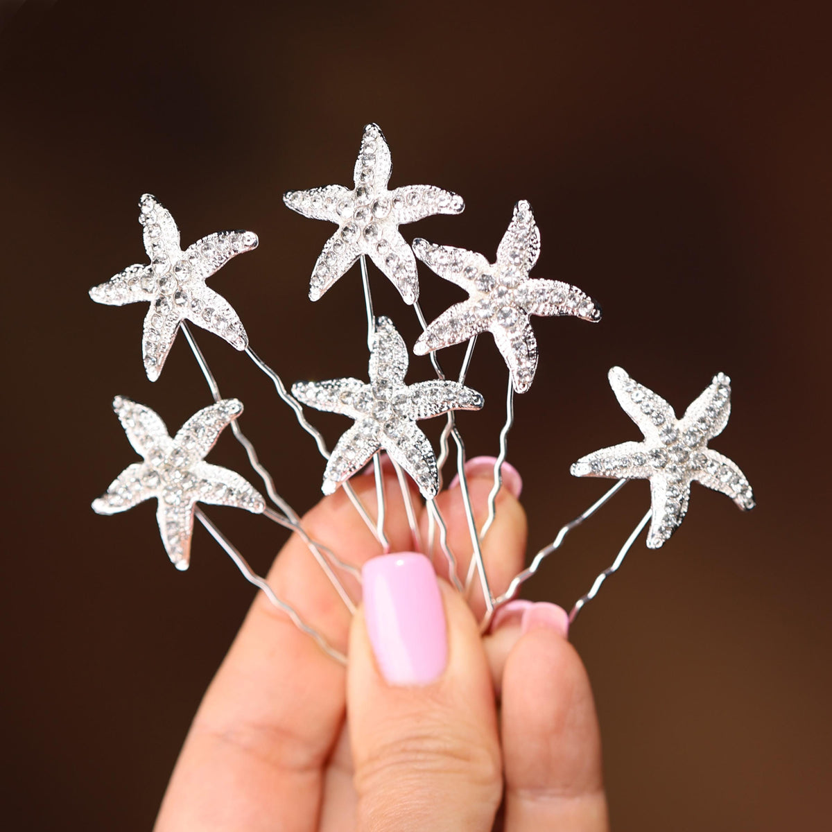 a hand holding a bunch of crystal starfish hair pins