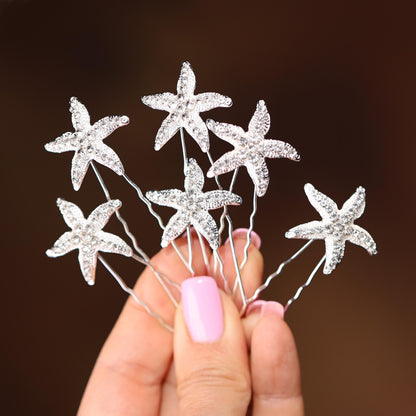 a hand holding a bunch of crystal starfish hair pins