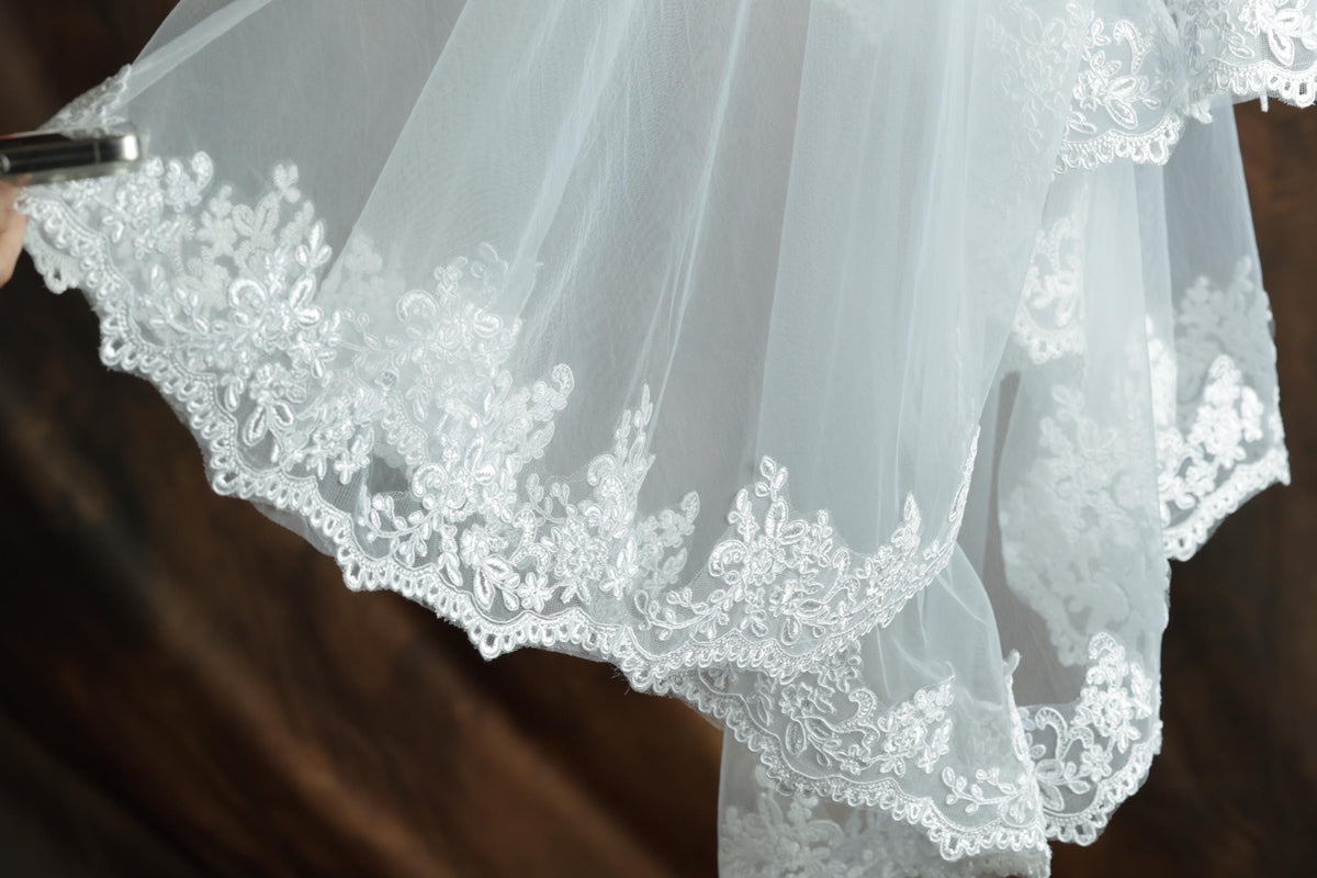 A close-up view of a delicate white wedding dress with intricate lace detailing.