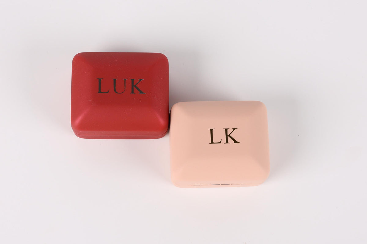 Two square boxes with the letters "LK" printed on them, one red and one beige.