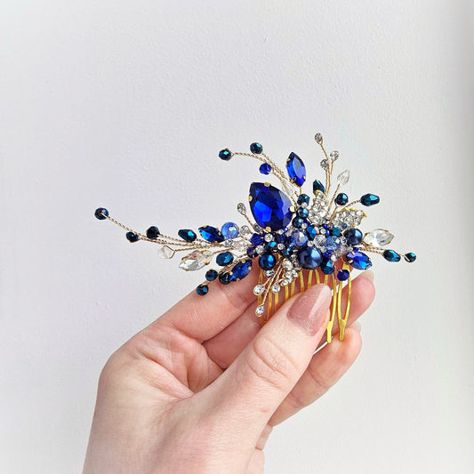 a hand holding a blue and gold hair comb
