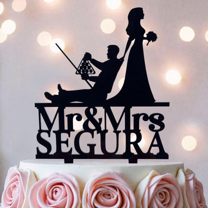 A silhouette of a bride and groom on a cake topper, with the text "Mr & Mrs Segura" below them.