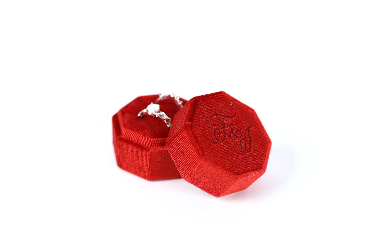 A red velvet box containing a diamond ring, with the ring visible inside the box.