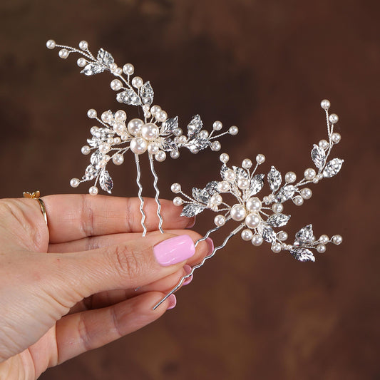 a hand holding a tiara with pearls and leaves
