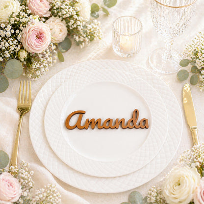 a table setting with a white plate, a wooden nameplate, and a floral arrangement.