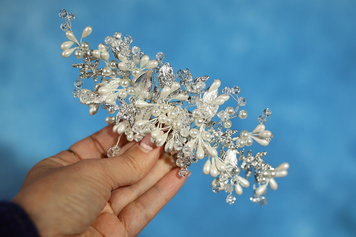 A hand holding a decorative piece of jewelry against a blue background.