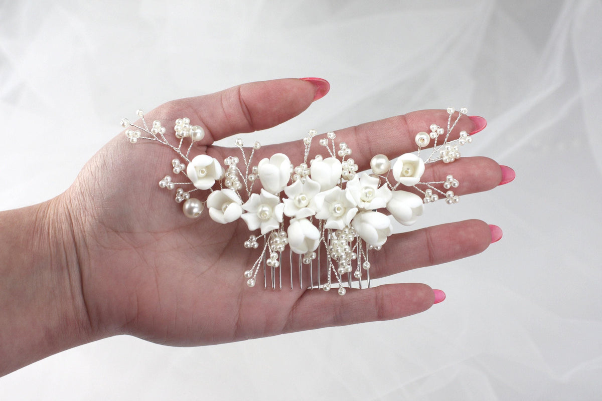 a woman's hand holding a white flower and pearl hair comb