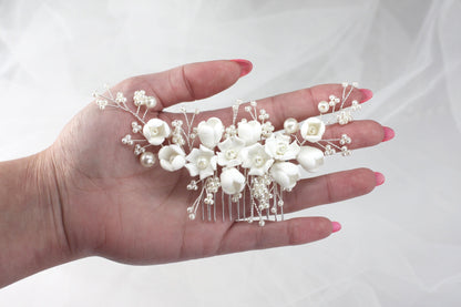 a woman's hand holding a white flower and pearl hair comb