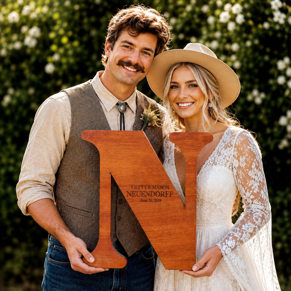 A man and a woman are holding a large wooden letter 'N' in front of them, smiling and posing for a photograph.