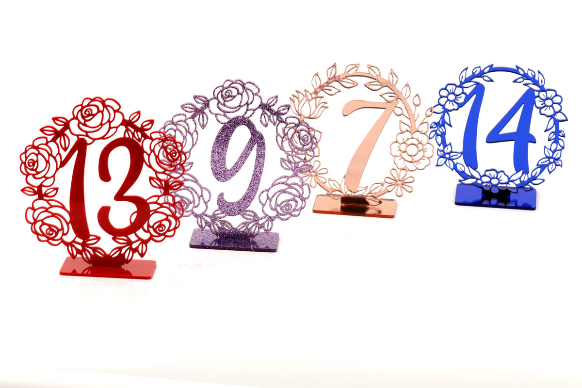 four decorative table number stands, each with a unique design and color.