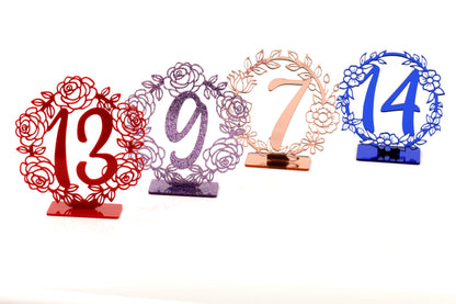four decorative table number stands, each with a unique design and color.