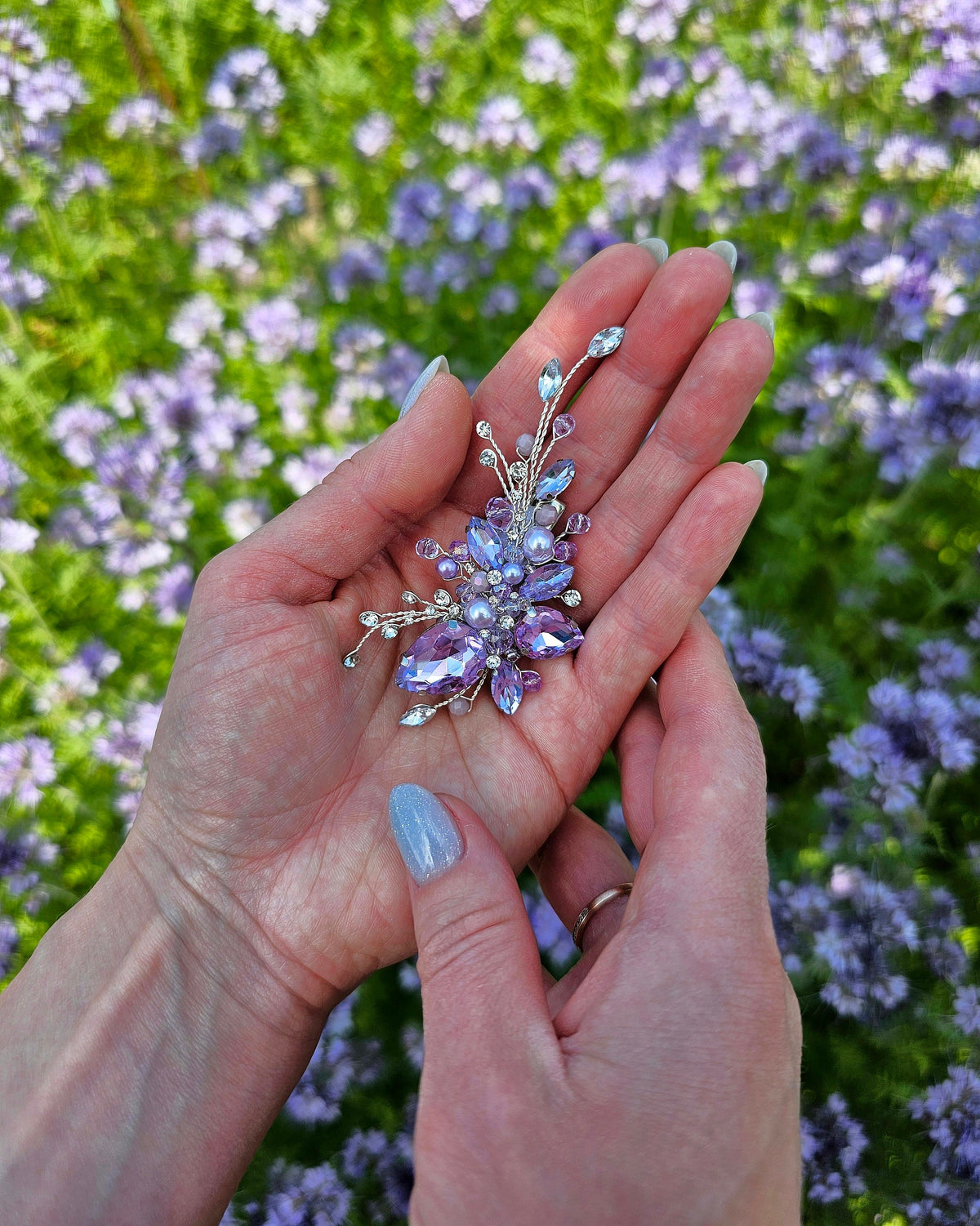 a woman's hand holding a ring with a flower on it