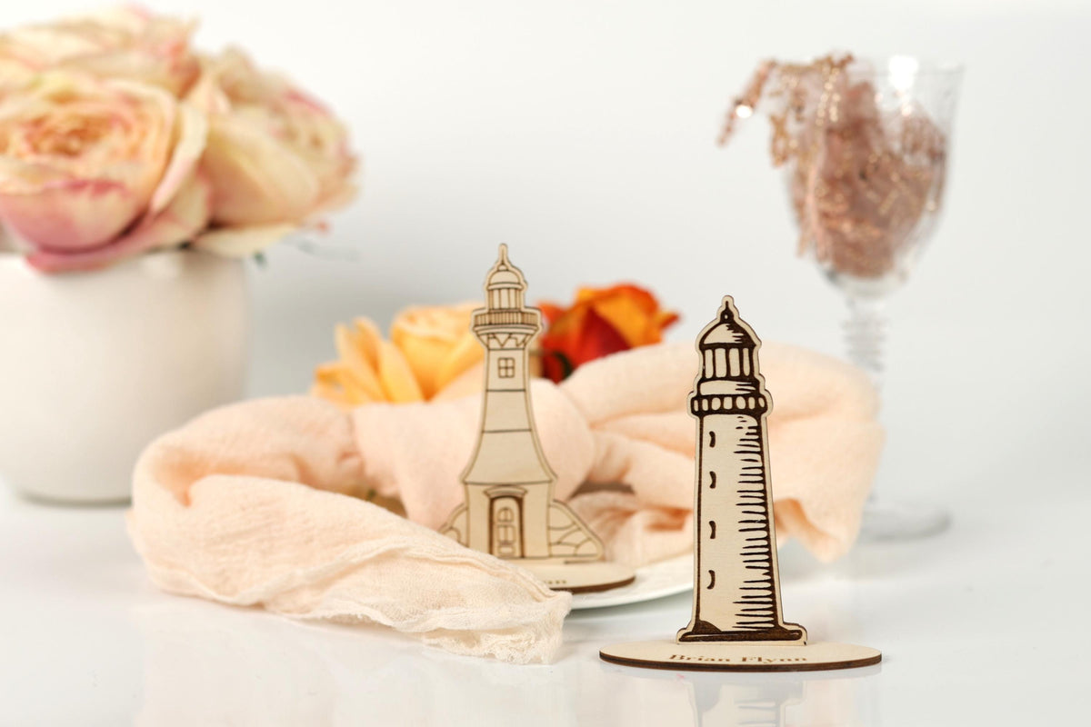 a wooden lighthouse and a vase of pink roses on a white surface.