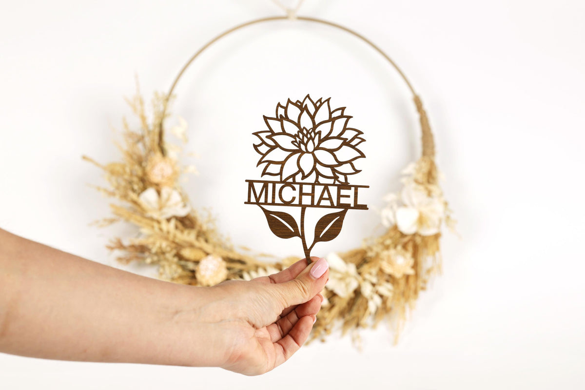 A hand holding a paper cutout of a flower with the name "MICHAEL" written on it.