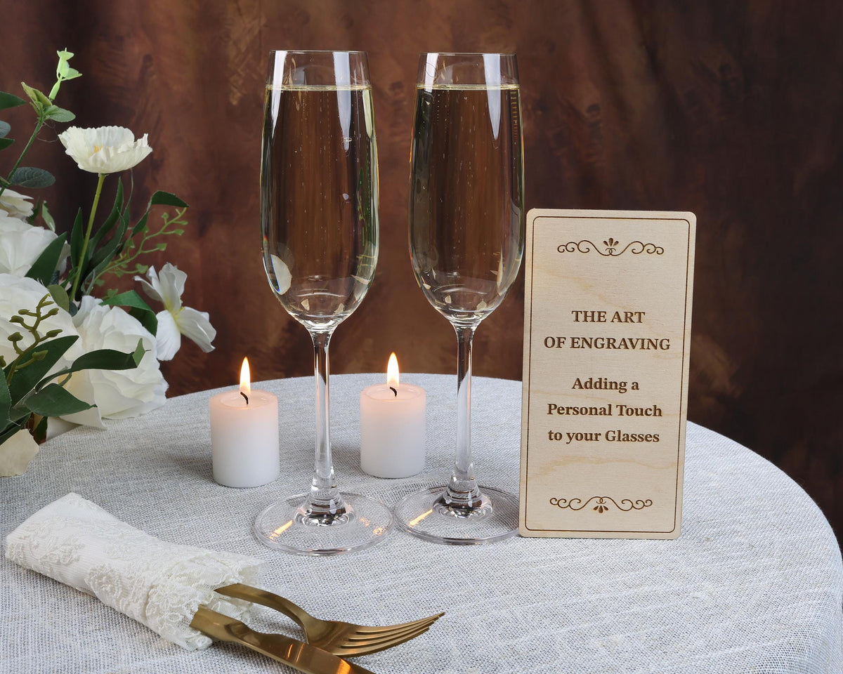 two glasses of champagne sitting on a table with a sign