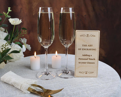 two glasses of champagne sitting on a table with a sign