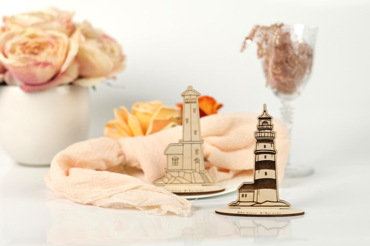 a wooden lighthouse and a vase of pink roses on a white surface.