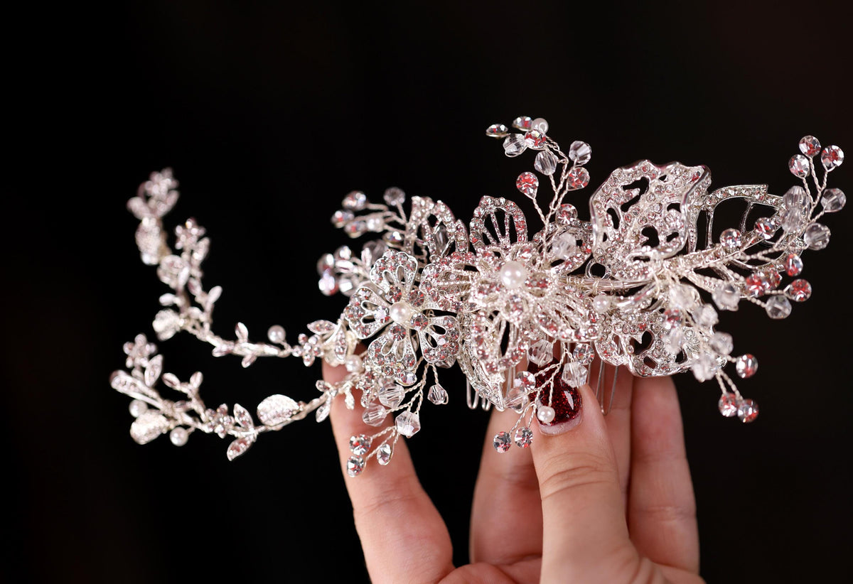 a hand holding a crystal and pearl tiara