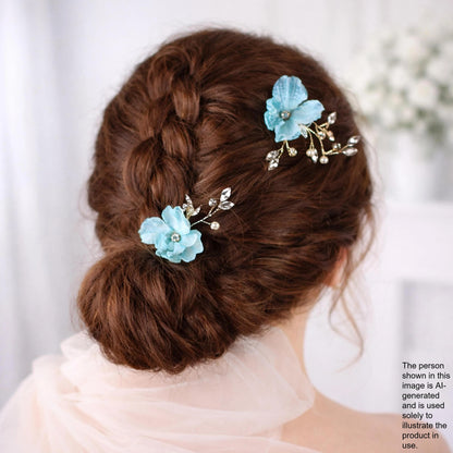 the back view of a woman's head with her hair styled in a bun, adorned with two blue flower hair clips.