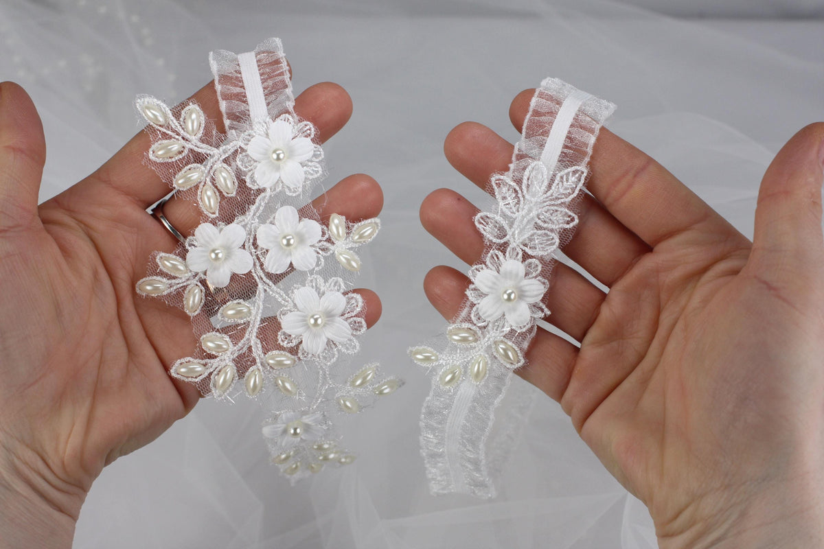 a pair of hands holding a pair of wedding garters