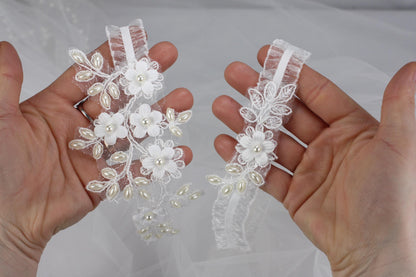 a pair of hands holding a pair of wedding garters