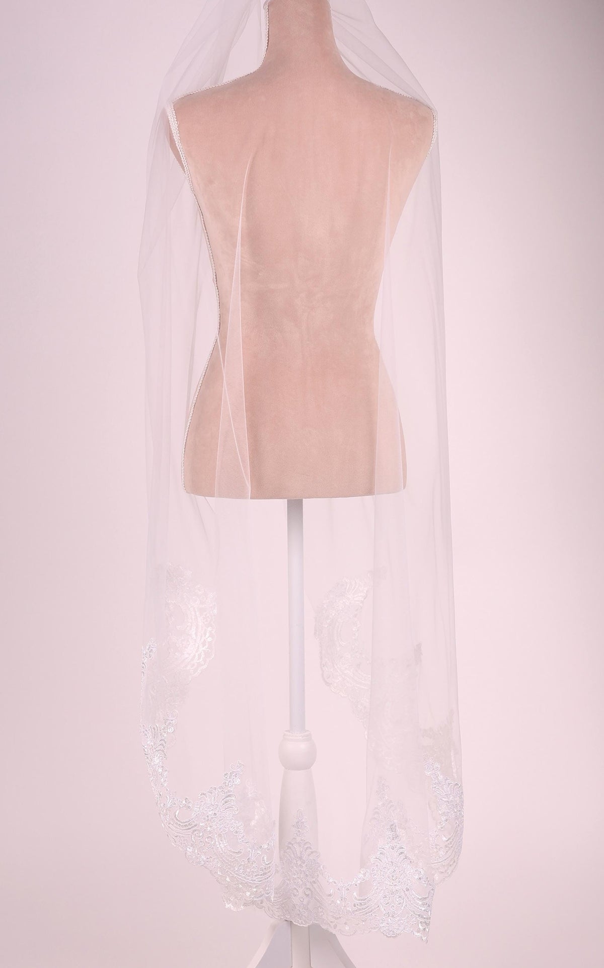 A mannequin wearing a white veil with a delicate lace pattern.