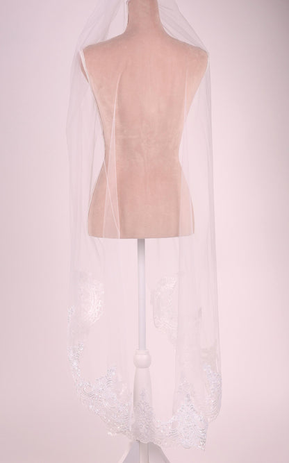 A mannequin wearing a white veil with a delicate lace pattern.