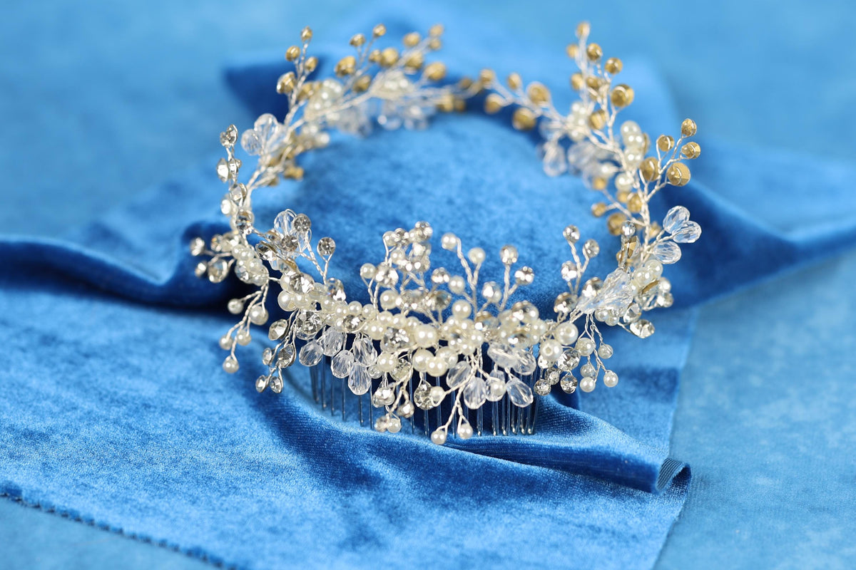 A decorative hair accessory with a floral design and clear gemstones is displayed on a blue velvet background.