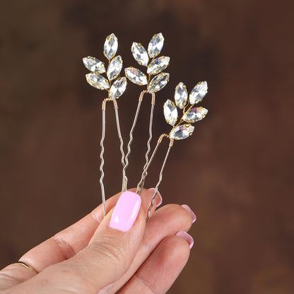 a hand holding a set of three crystal hair pins