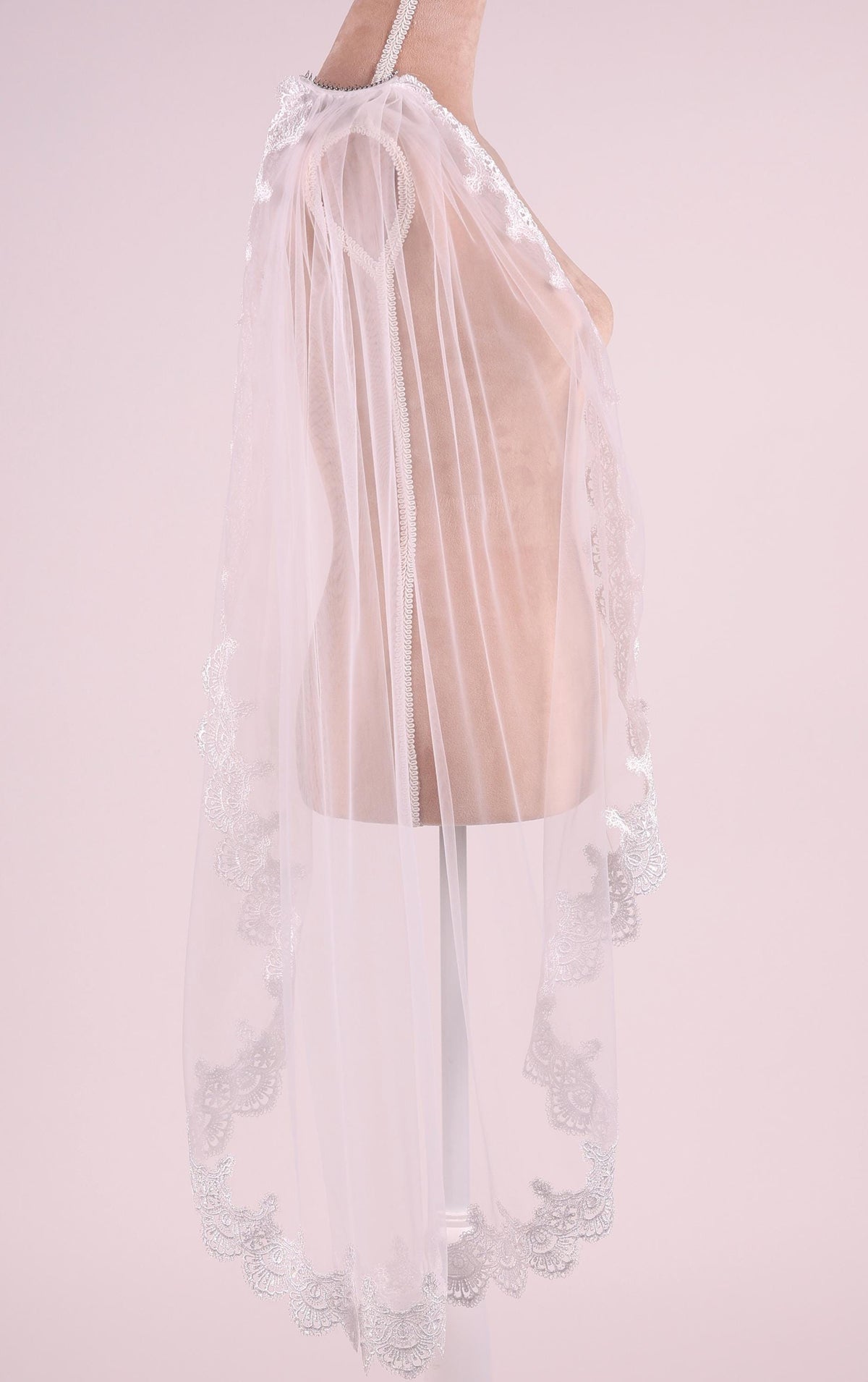 A mannequin wearing a white lace veil with a delicate floral pattern.