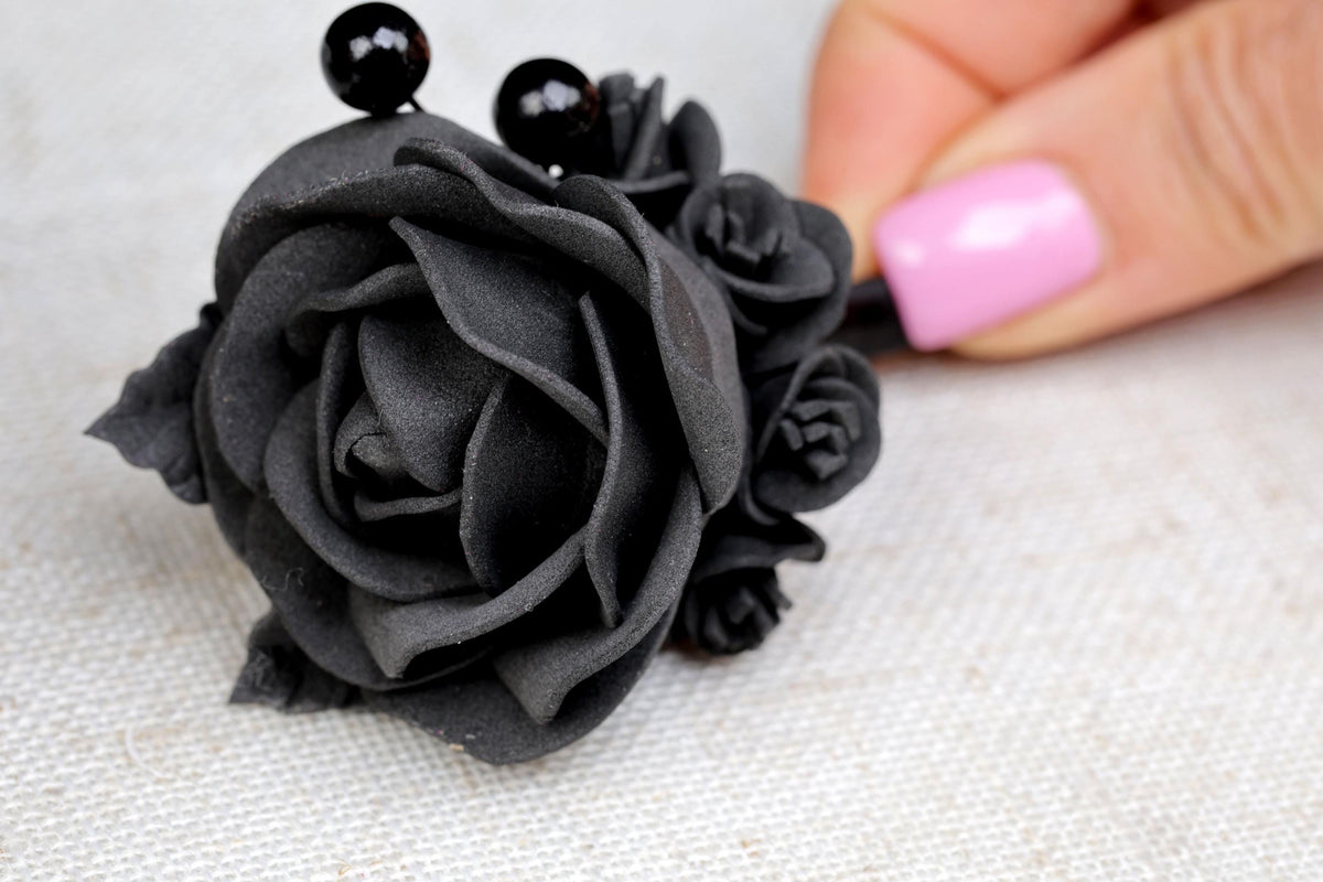 a woman's hand is holding a black rose