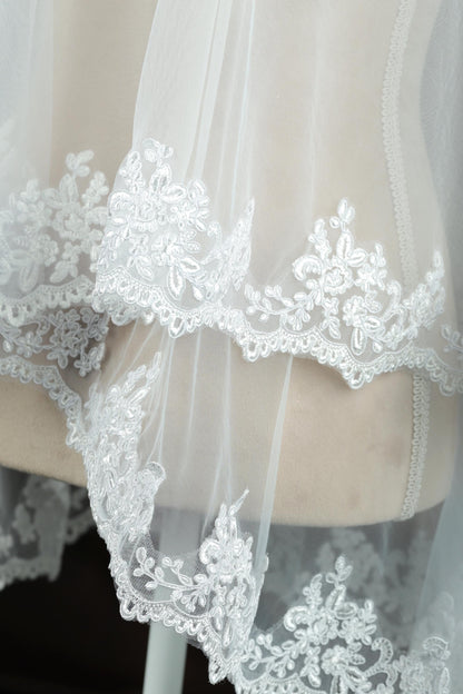 A close-up view of a delicate, white lace veil with intricate floral embroidery.