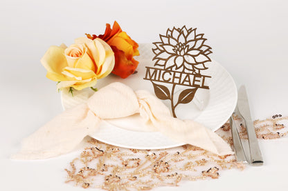 a white plate with a floral centerpiece, a nameplate, and some decorative elements such as flowers and beaded ornaments.