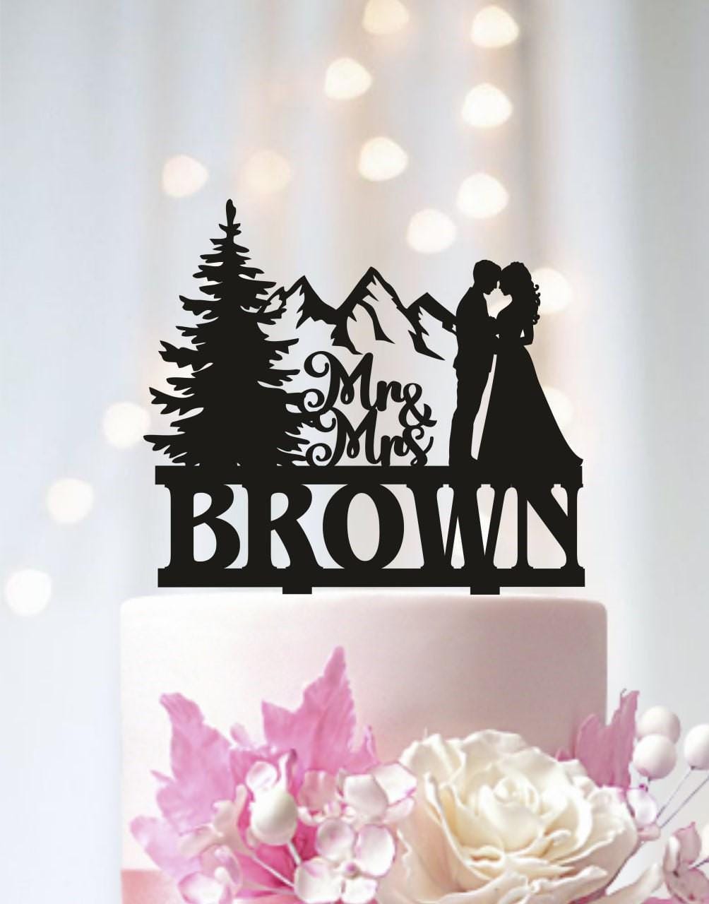 A black silhouette of a couple embracing, with the words "Mrs & Brown" written above them, on a cake topper.
