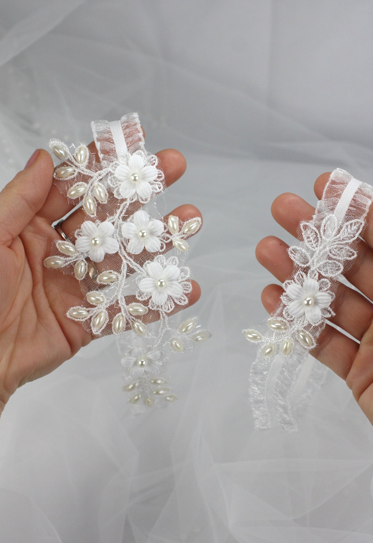 a pair of hands holding a pair of wedding garters