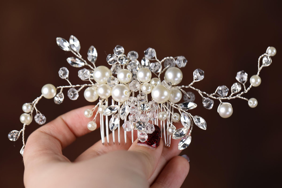 a hand holding a bridal hair comb with pearls and crystals