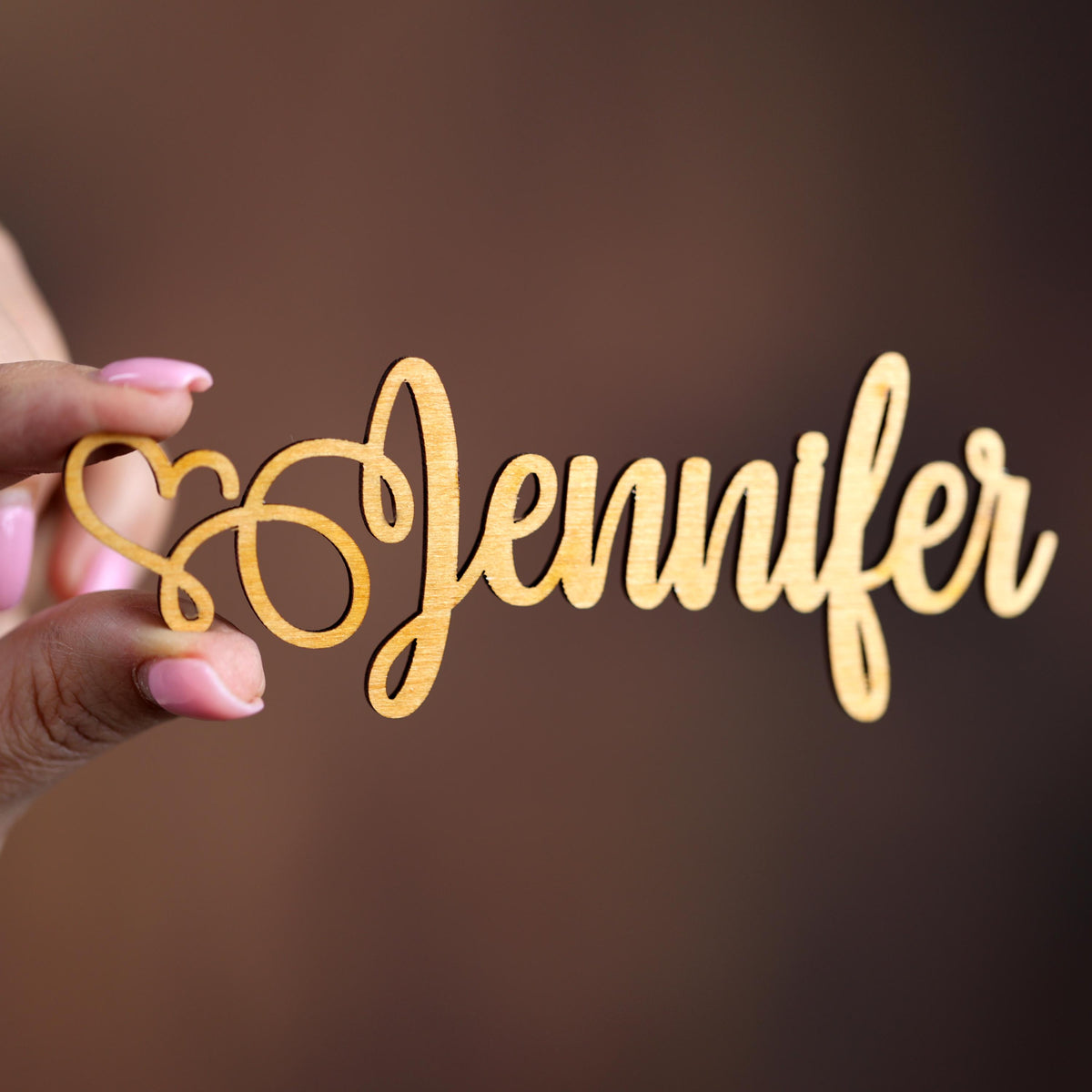 a person holding a piece of wood with the word jenny written on it
