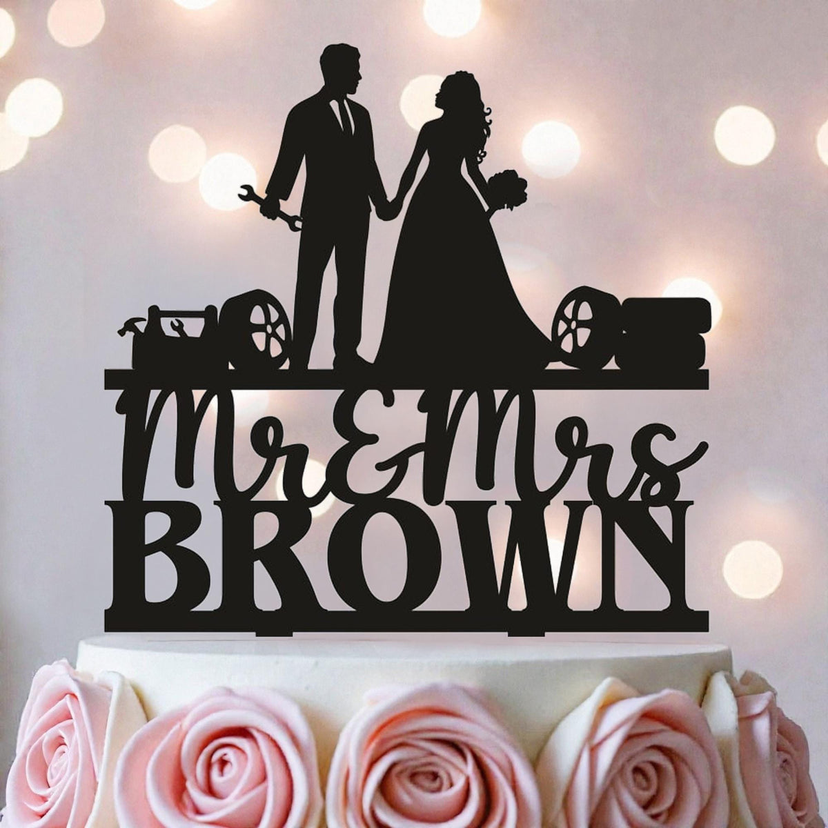 A silhouette of a bride and groom on a wedding cake topper, with the text "Mr & Mrs Brown" below them.
