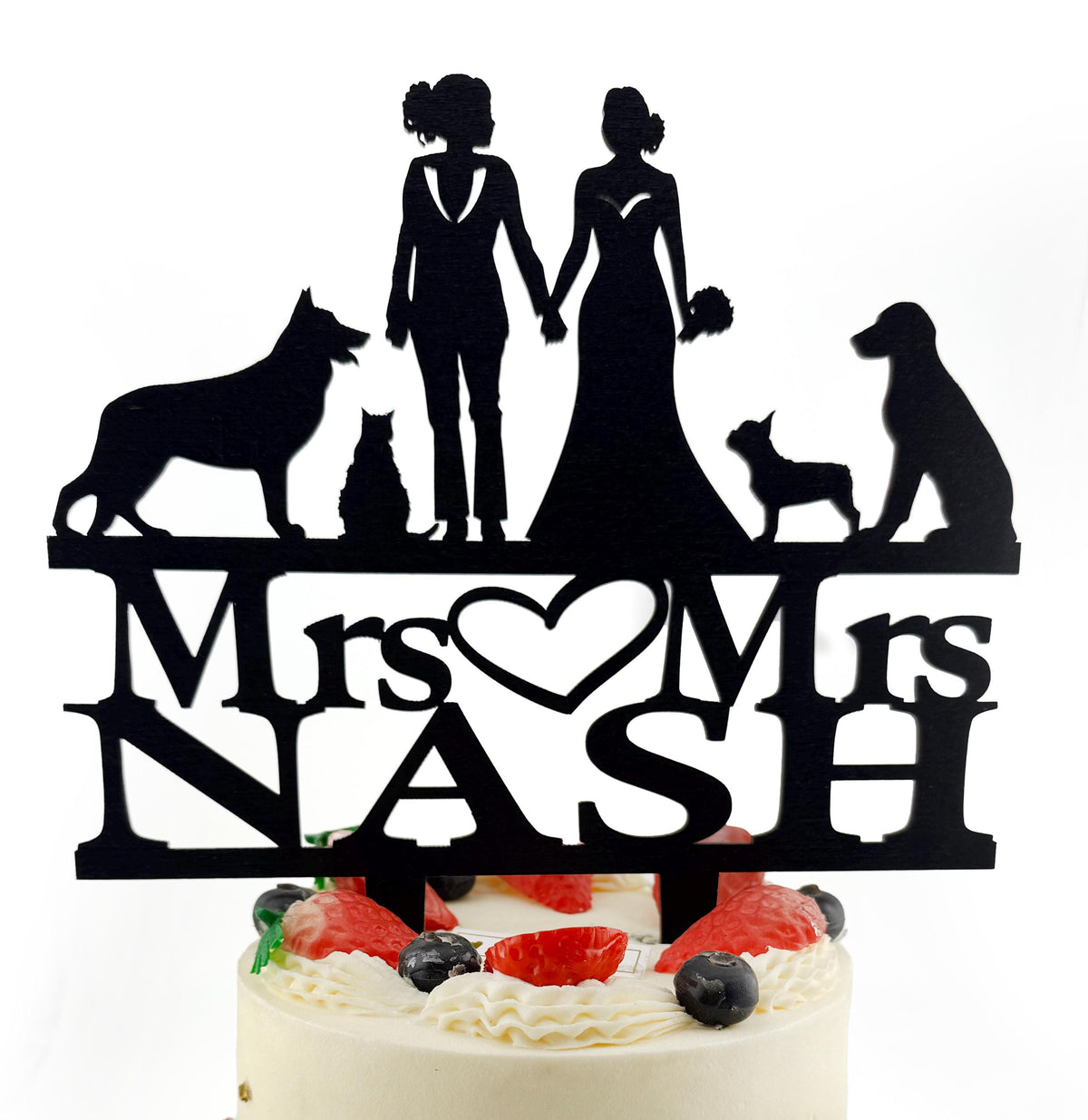 A silhouette of a bride and groom holding hands, along with silhouettes of their pets, is displayed on a cake topper.