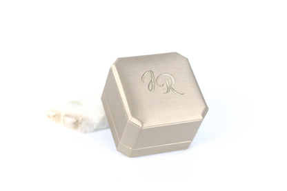 A silver-colored hexagonal box with a logo on it, placed on a white background.